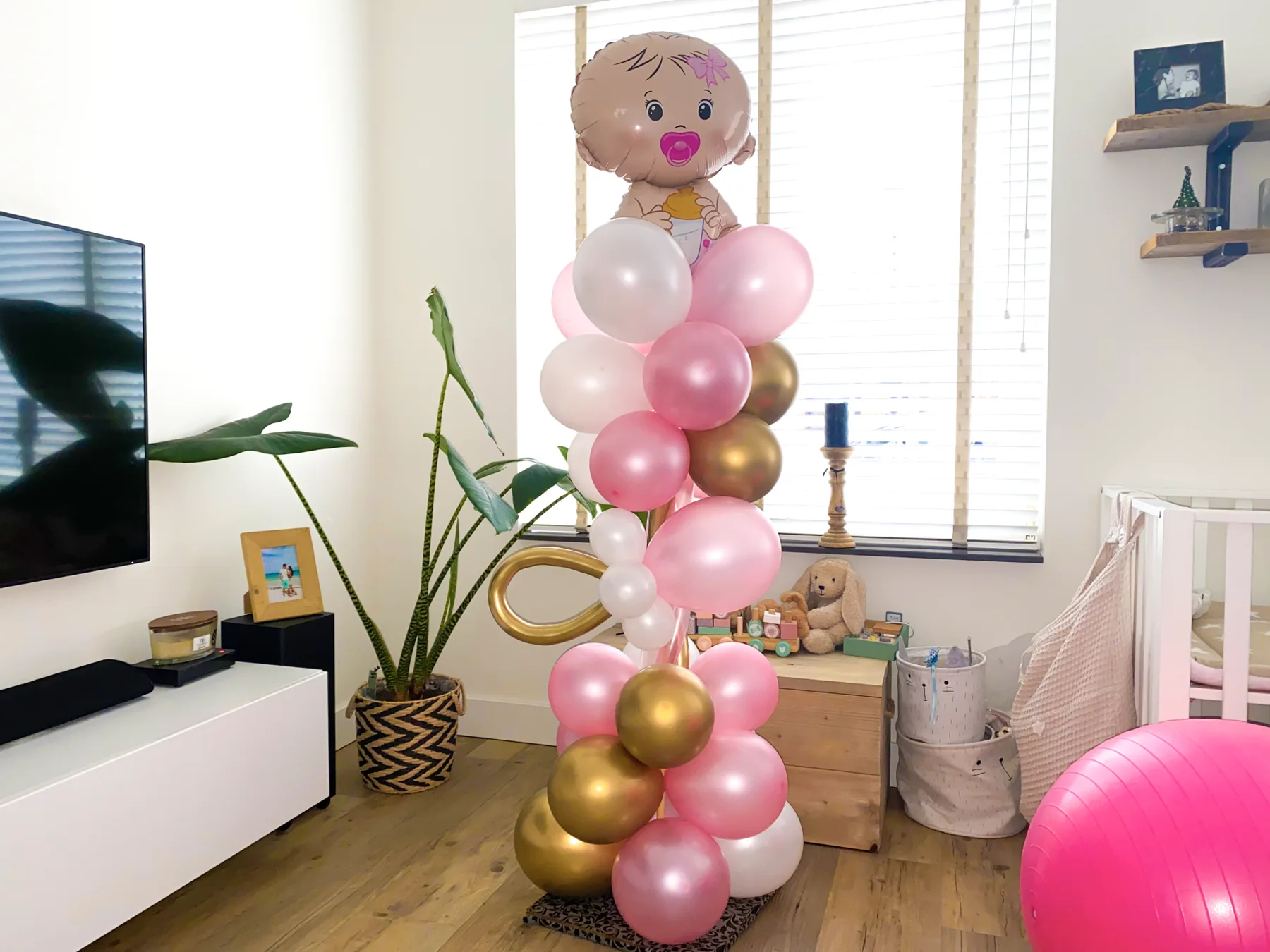 Roze en gouden ballonnenpilaar voor de geboorte van een meisje