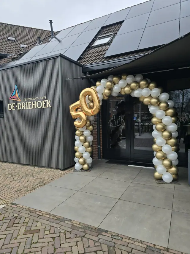 Goud-witte ballonnenboog bij de entree van een restaurant voor een 50-jarig jubileum