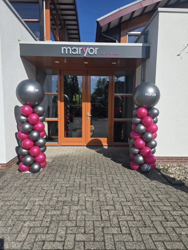Twee roze en antraciete ballonnenpilaren met bedrijfslogo