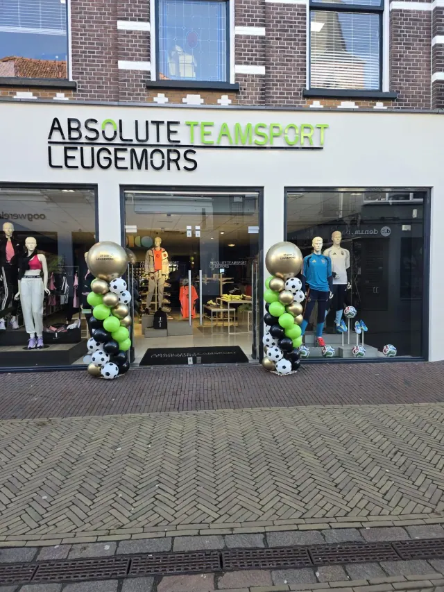 Twee sportieve ballonnenpilaren met voetbalballonnen bij een winkel