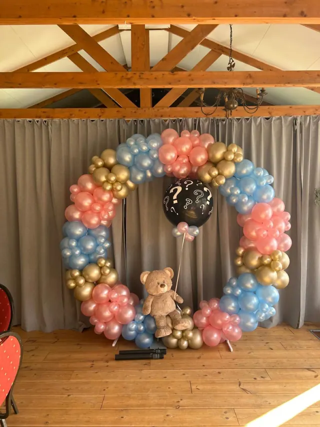 Ronde fotohoek met roze, blauwe en gouden ballonnen voor een gender reveal